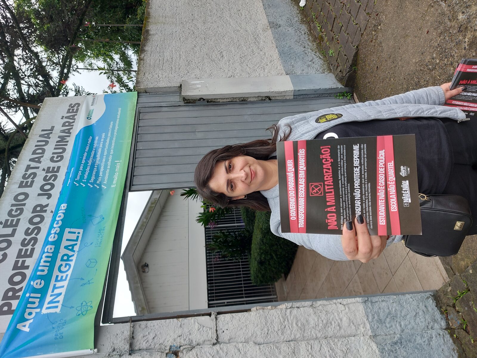 Professora Amábile Marchi em protesto contra a privatização das escolas públicas no Paraná segurando cartaz 'Não à Militarização'